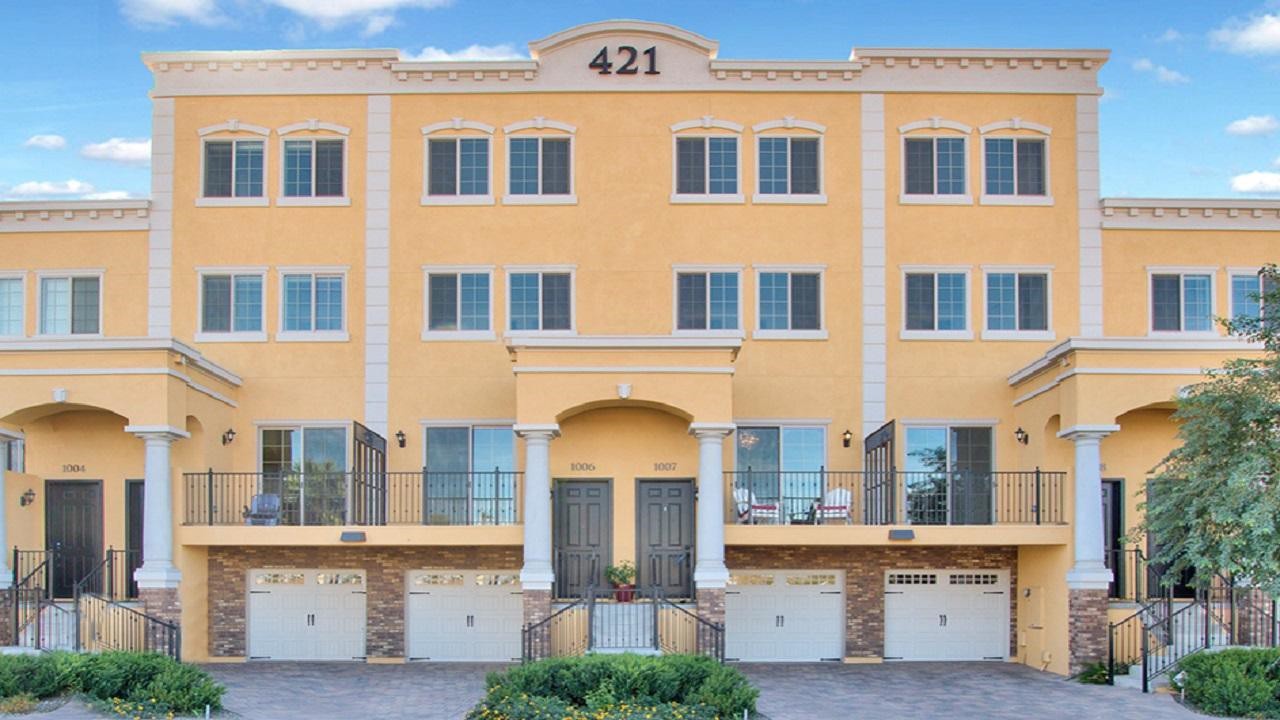 A yellow building with two garage doors and windows.